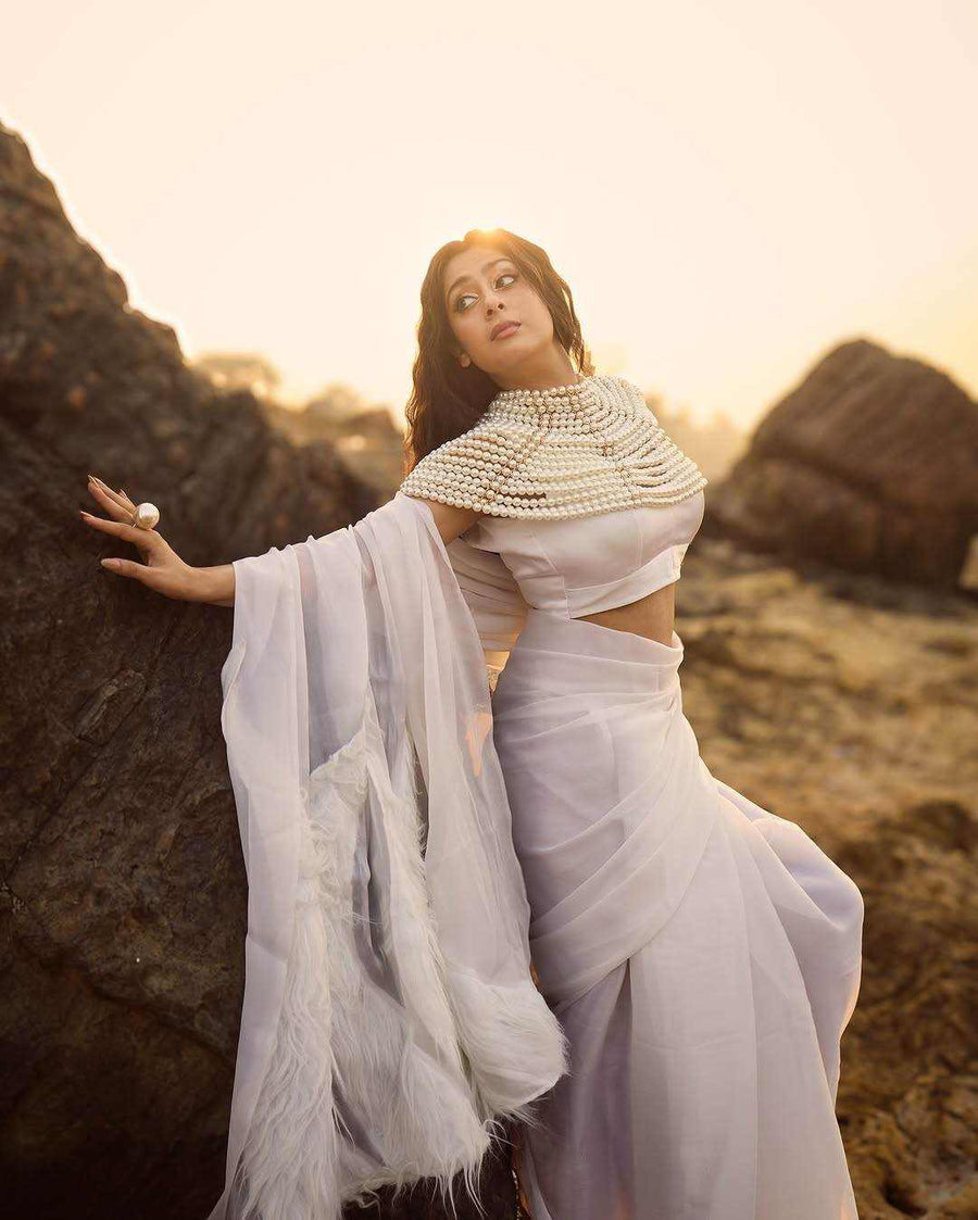 Pearl Cape Top with layered white pearl strands forming a sculptural shoulder cape over a white outfit